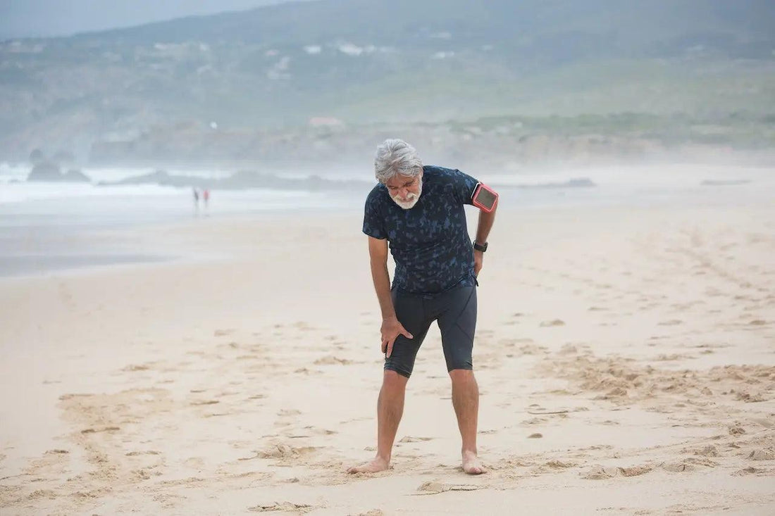 A man on the beach holding on to his back