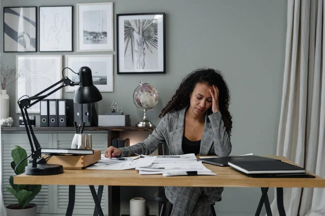 a tired woman working on her stylus and laptop at her desk