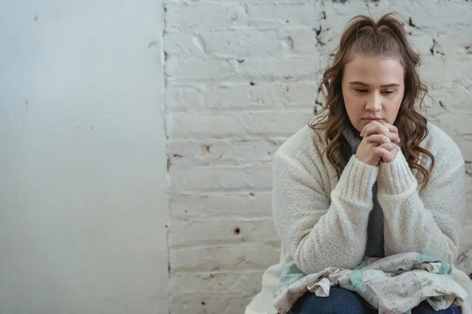 an anxious woman sitting next to a white wall
