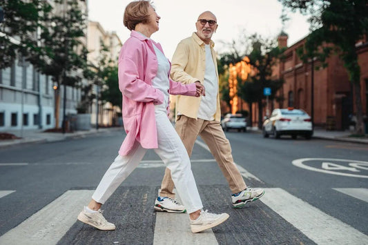 a happy elderly couple walking across the street holding hands