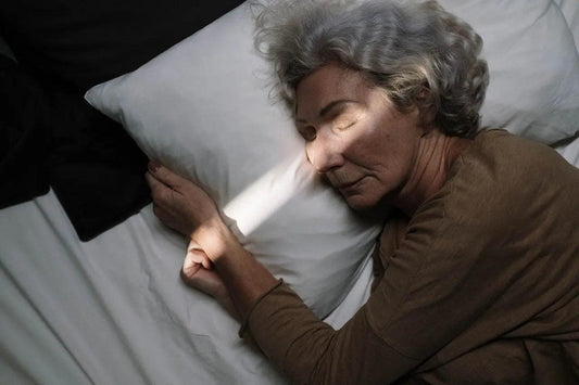a senior woman wearing brown sleeping on a white bed