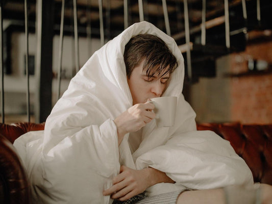 a man with a cold sitting down drinking tea