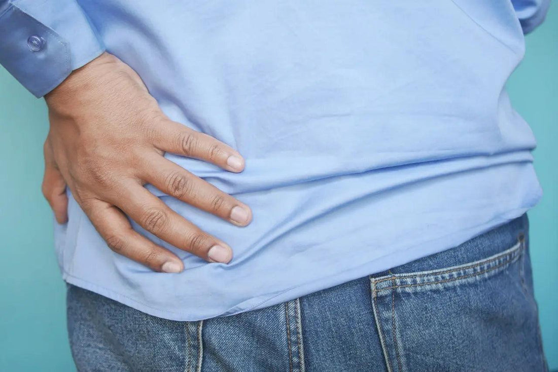 a man in a blue shirt grabbing his hip in pain